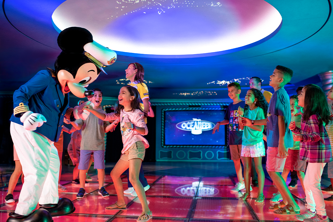 Vêtu d'un costume de capitaine de navire, Mickey Mouse danse avec plusieurs enfants