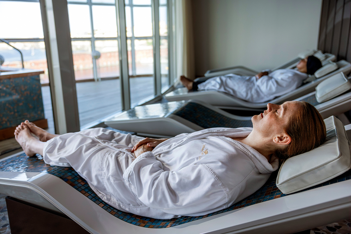 Une femme se détend sur le ventre avec des pierres chaudes sur le dos