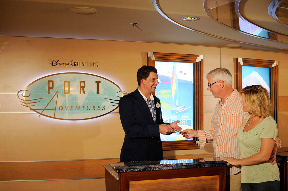 Un membre de l'équipe aide des passagers à un centre d'assistance lors d'une croisière Disney