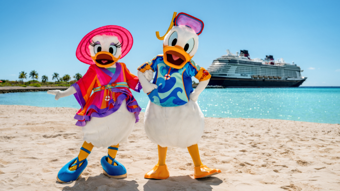 Daisy Duck et Donald Duck en tenue de plage posant sur la plage à Disney Castaway Cay près d’un navire de la Disney Cruise Line