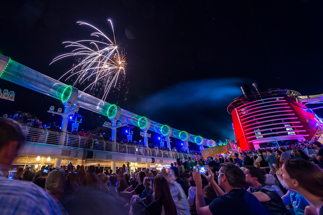 Une foule regarde des feux d'artifice au-dessus du pont d'un navire de croisière Disney
