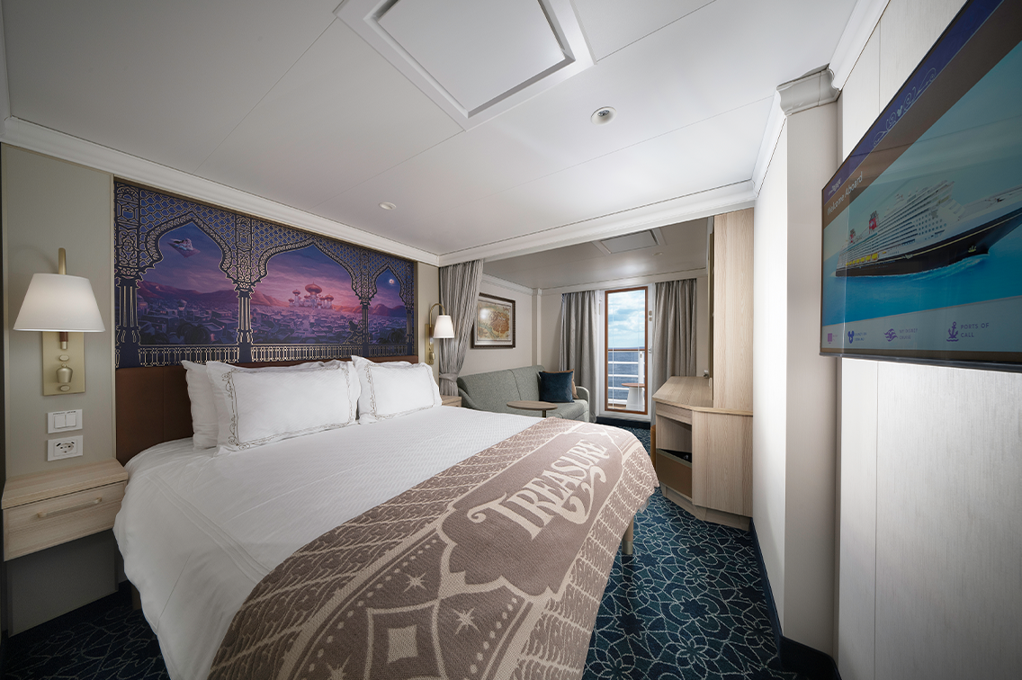 Une suite luxueuse avec un lit, des Suvres d'art murales, 2 lampes votives, un coin salon avec un canapé et un accès à un balcon privé