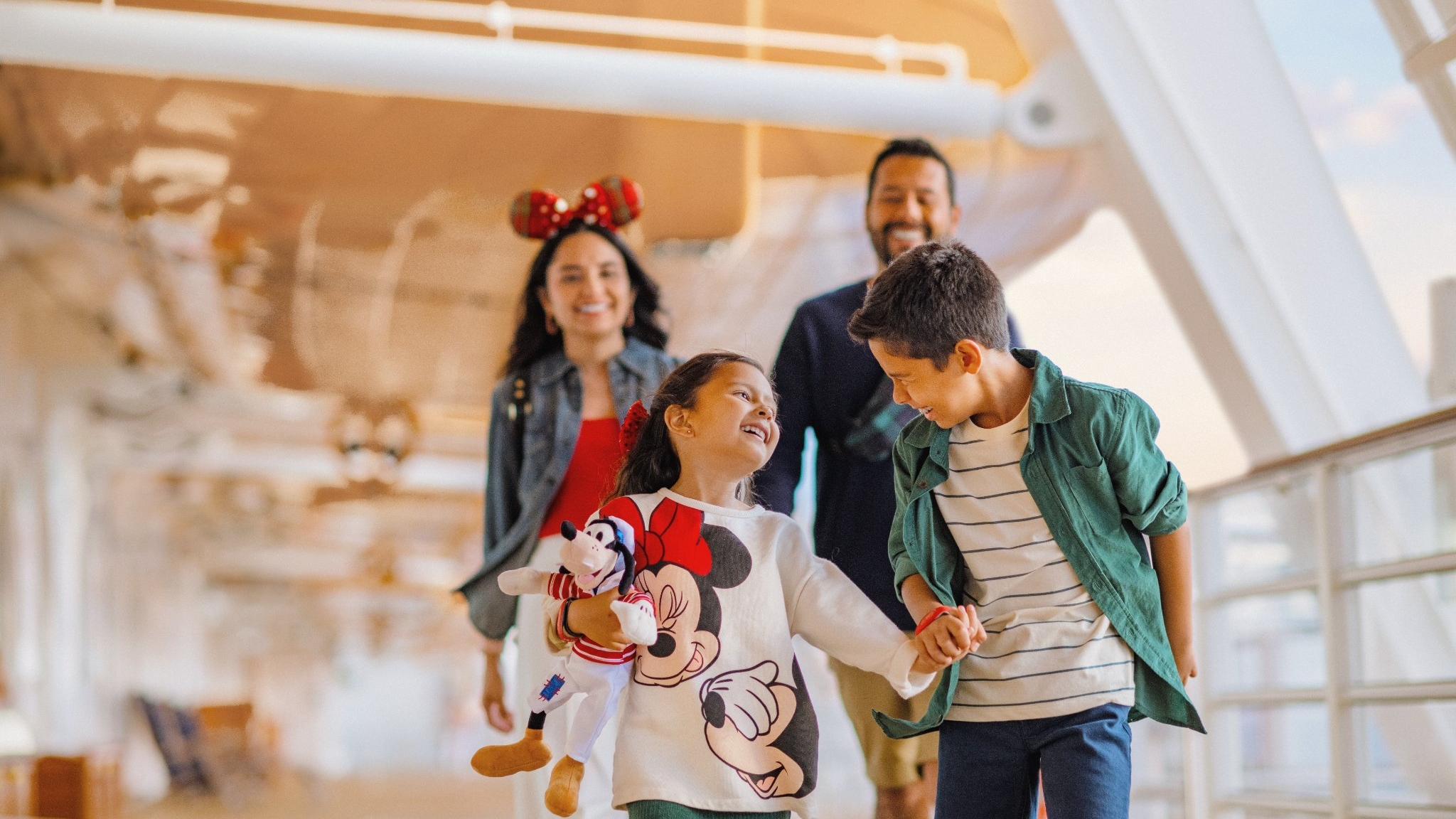 Une famille souriante vêtue de tenues inspirées de Disney se promène    ensemble sur le pont d’un navire de la Disney Cruise Line.