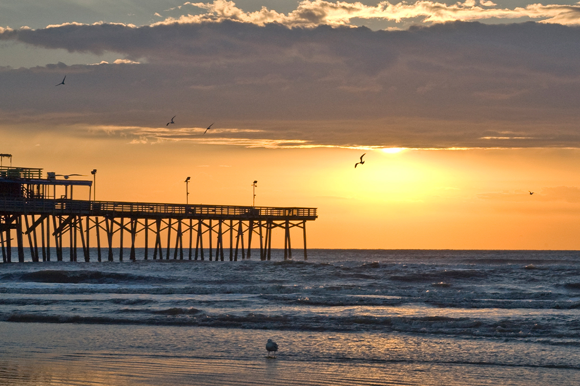 Une jetée en bois s'étend dans l'océan au coucher du soleil