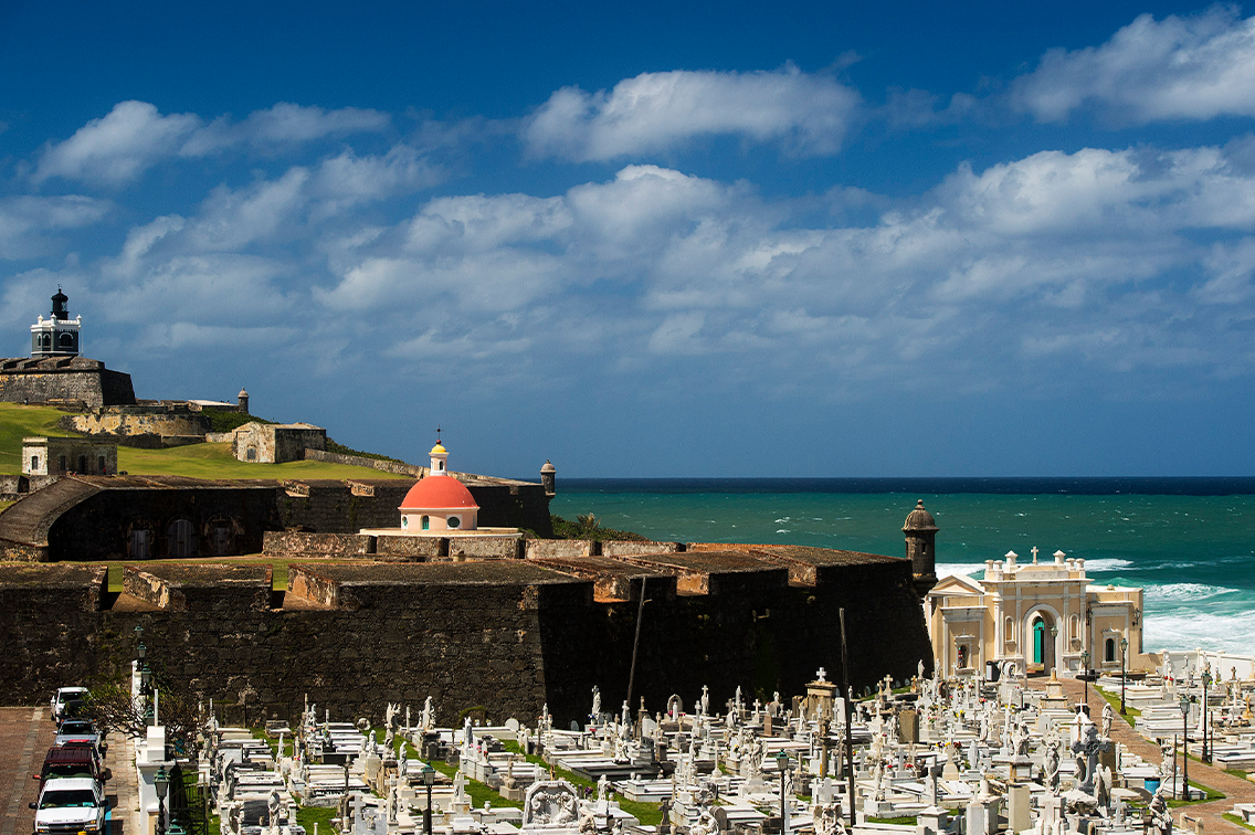 Des gens marchent le long des bâtiments et des murs du 17e siècle qui entourent la baie de San Juan