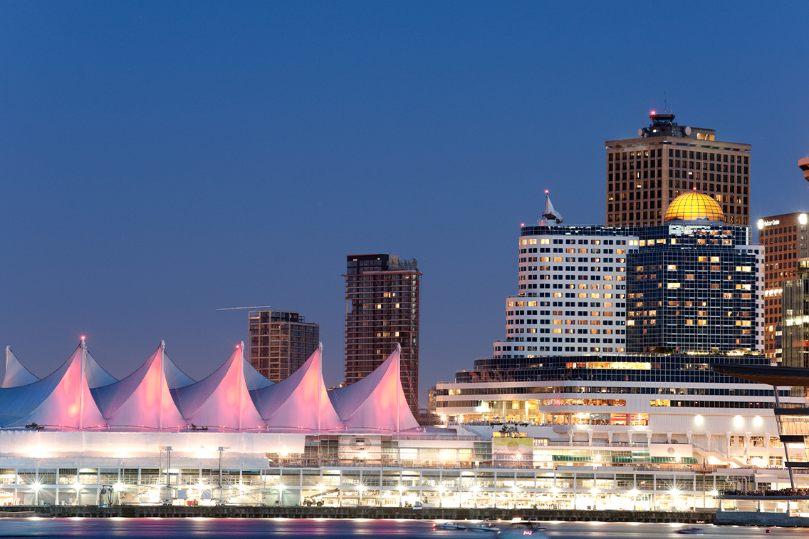 Une rangée de toits en forme de tente près du port de Vancouver, à côté de gratte-ciel, la nuit