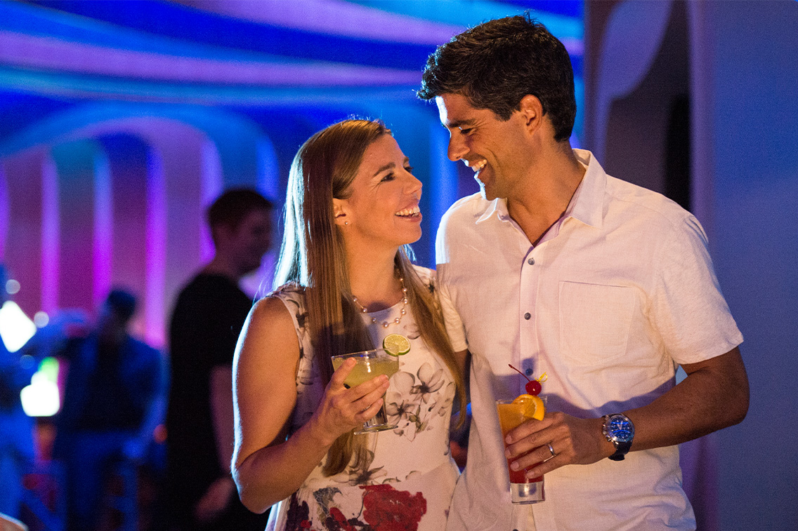 Un couple sourit en tenant des cocktails