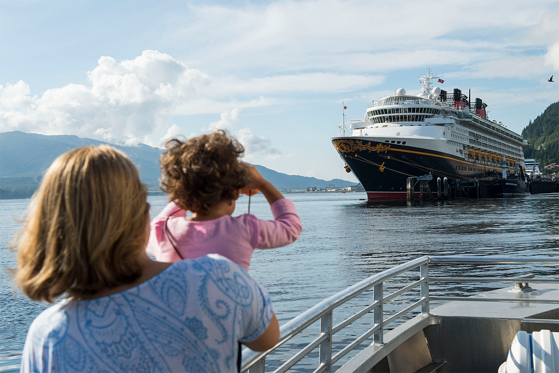 Une femme et une fille regardent un navire de croisière près des montagnes