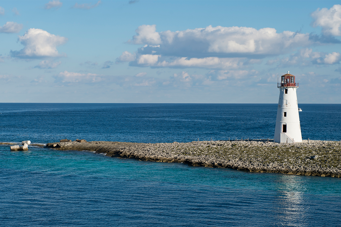 Un navire de croisière Disney près d'un rivage des Caraïbes, avec des palmiers et des drapeaux nautiques